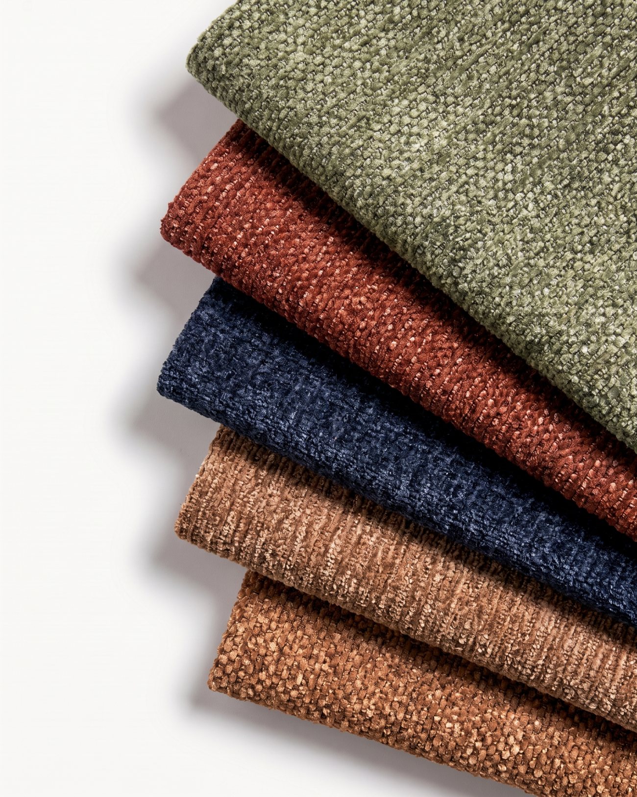 Folded Floom fabric samples in olive, rust, navy and camel chenille