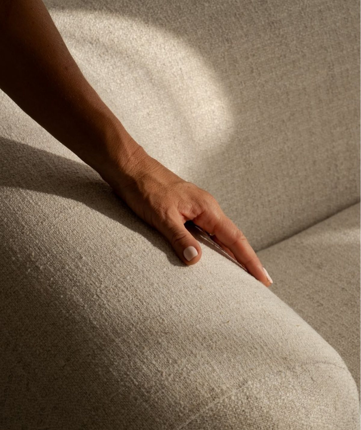 A hand smoothing the textured upholstery of a Floom sofa