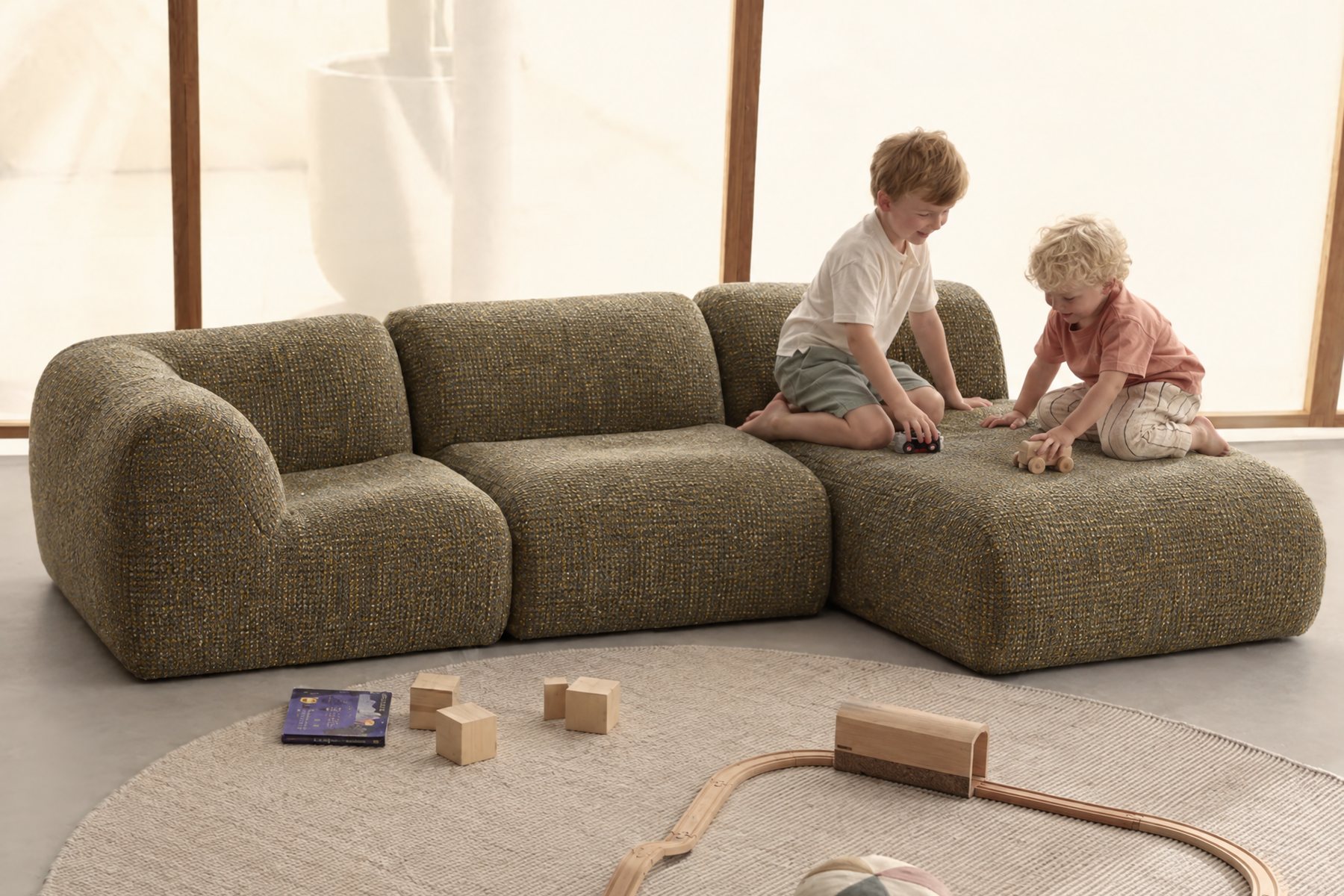 Two children playing on a green modular Floom sofa in a bright room